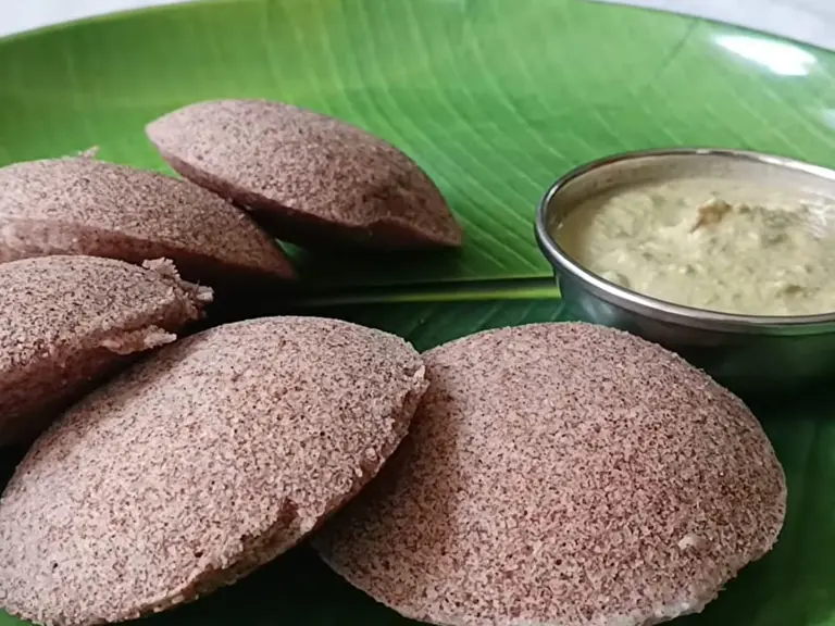 Steamed ragi idli served on a banana leaf with chutney